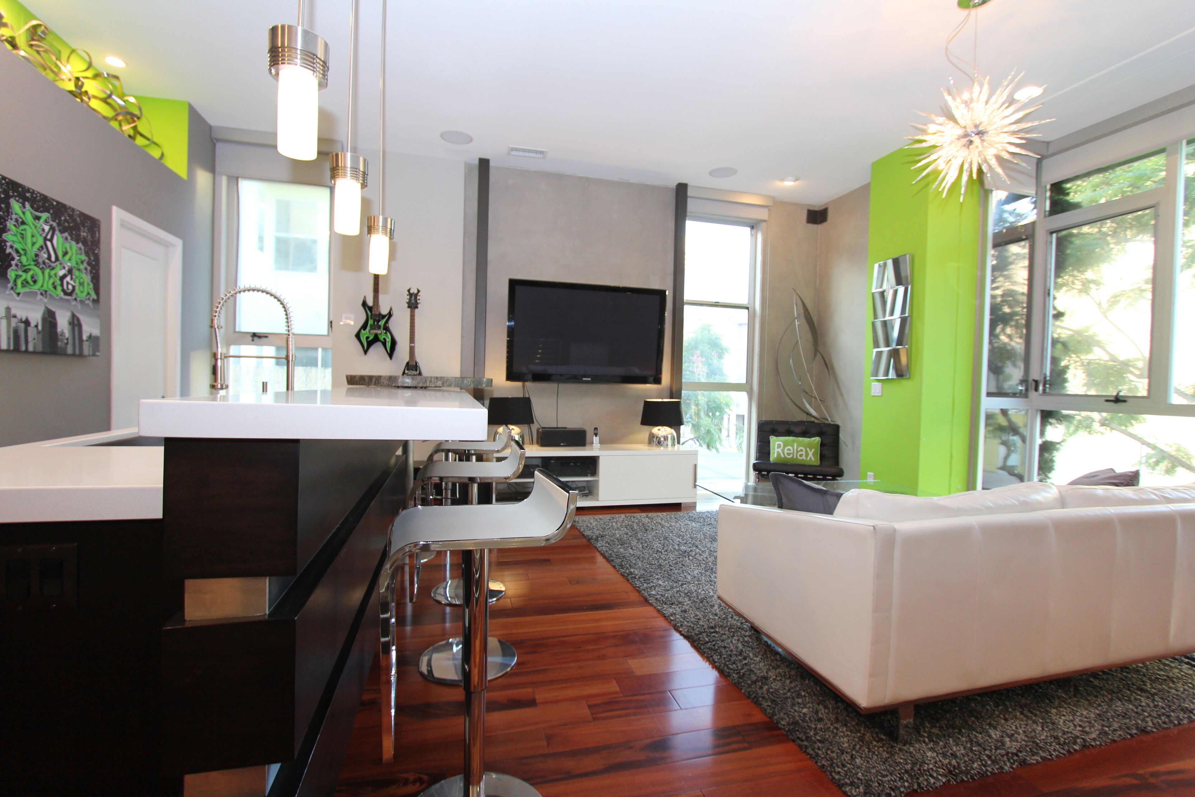 A modern kitchen with a large island, bar stools, and a flat-screen TV.