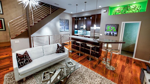 Eine moderne Küche mit Barbereich, einer Treppe und einem Wohnzimmer mit Sofa und Couchtisch.