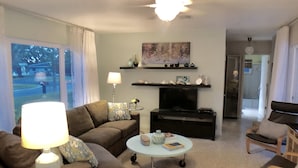 A living room with a sofa, coffee table, TV, and decorative items. - 4 BR/3BA Poolhouse is 4 miles from the famous Siesta Key Beach (Sarasota)
