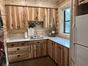 Compact kitchen with sink, stainless steel faucet, and a refrigerator.