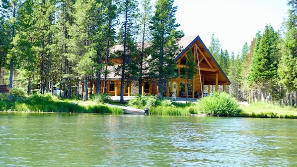 Escape to a serene lakeside retreat surrounded by a dense forest, with a welcoming porch and stunning views.