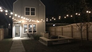 Een tweelaags huis met een overdekte veranda en lichtjes.