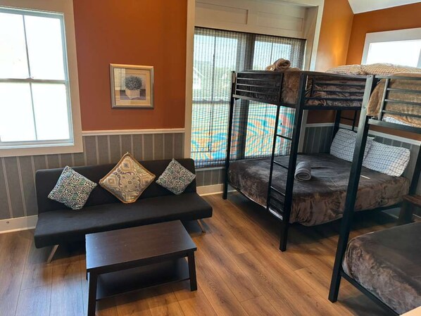A room with a bunk bed, a sofa with patterned cushions, a small table, and a window with a view of a tennis court. - Classy Stay only 2 Miles from Downtown - Sleeps 12 (Nashville)