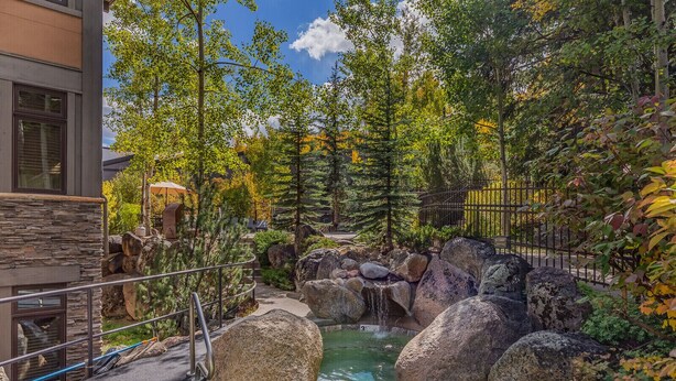 A stone building with a pool area featuring large rocks and a waterfall. - Seconds to mall and slope, 2 hot tubs,1 pool, small gym, fireplaces (Snowmass Village)