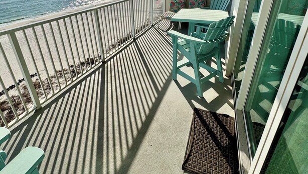 Een balkon met uitzicht op de oceaan, met een tafel en stoelen.
