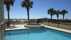 Zwembad met een jacuzzi, omgeven door palmbomen en uitzicht op het strand.