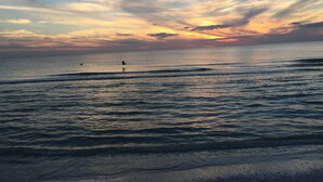Ein Strand mit Wellen und einem Sonnenuntergang.