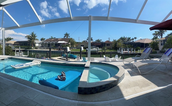 A swimming pool with a diving board, lounge chairs, and a covered area.