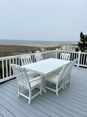 A white wooden deck with a table and chairs, overlooking a beach. - Beautiful Beachfront Retreat on Broadkill Beach. Perfect for couples & families. (Milton)