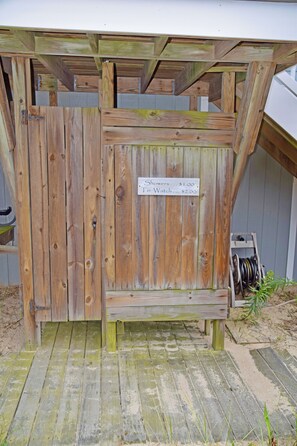 A wooden structure with a sign indicating prices for showers and a toilet watch. - Beautiful Beachfront Retreat on Broadkill Beach. Perfect for couples & families. (Milton)