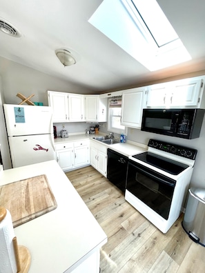 A compact kitchen with white cabinets, a built-in microwave, and a dishwasher.