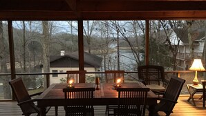 A wooden deck with a table and chairs, a lamp, and a view of a lake and trees. - Ultimate Getaway Lake Cumberland, Great Location, easy access to water (Jamestown)