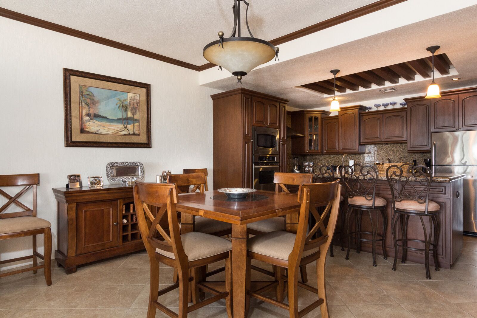 A kitchen with wooden cabinets, a dining table with chairs, and a hanging light fixture.