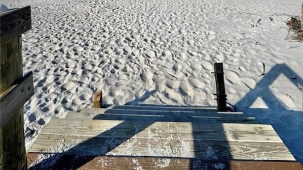 Ein Strand mit einer hölzernen Promenade, die zum Wasser führt.