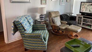 A living room with a patterned armchair, a recliner, a TV, and framed artwork on the wall. - Flop On In: Bring your flipflops and enjoy the best of Myrtle Beach (Myrtle Beach)