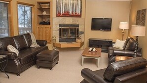 Ein Wohnzimmer mit Kamin, Ledersofas, Fernseher und Lampe.