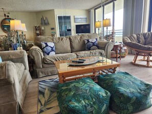 A living room with a sofa, armchairs, a coffee table, and a view of the sea through large windows. - 10/10 EXCEPTIONAL!!!-173 REVIEWS-DAYTONA BEACH-2BD/2BA-RENOVATED-WELL STOCKED (Daytona Beach Shores)