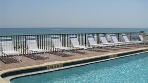 Ein Pool mit Liegestühlen und einer Brüstung, mit freiem Blick auf den Ozean.