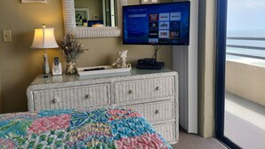 Ein Hotelzimmer mit einem Bett, einem Schminktisch, einem Fernseher der Roku TV-Schnittstelle sowie einer Lampe und einer dekorativen Muschel.