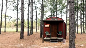 Una pequeña cabaña roja con un letrero que dice "Schoolhouse" en un área boscosa.