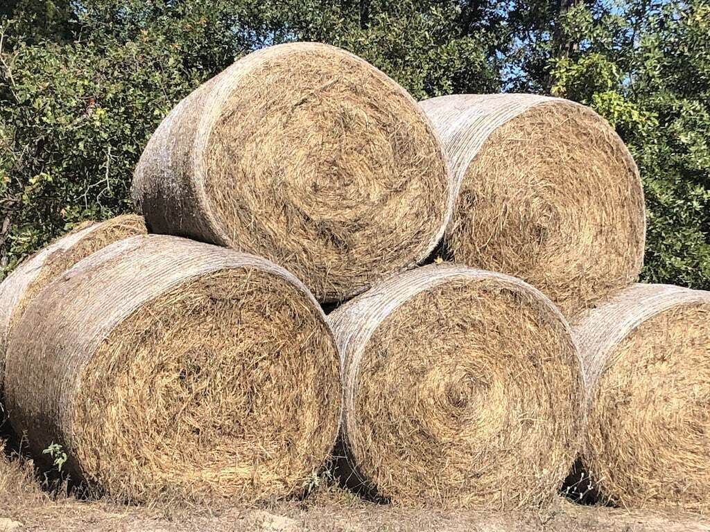 A stack of large hay bales in a field.