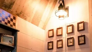 Habitación con vigas de madera en el techo, un diseño de baldosas de ajedrez en la pared izquierda y una lámpara fijada a la pared.