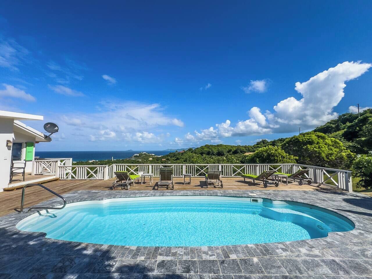 A swimming pool with lounge chairs and a view of the ocean.