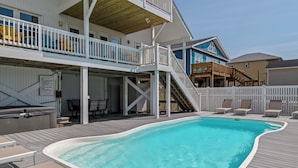 A pool area with a wooden deck, lounge chairs, and a hot tub. - Luxury Oceanfront Retreat: Concierge Beach Tent Service, Heated Pool & Hot Tub (Holden Beach)