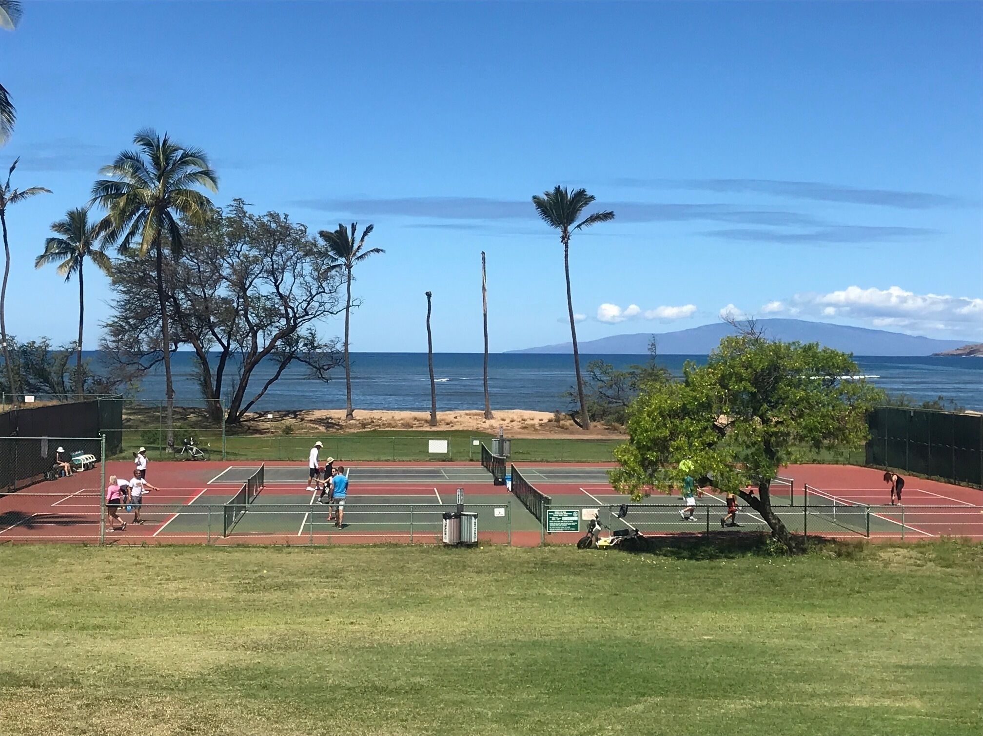 A tennis court with a view of the ocean and mountains in the background.