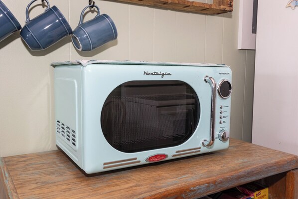 Horno tostador de estilo retro con exterior blanco y interior negro, sobre una superficie de madera.