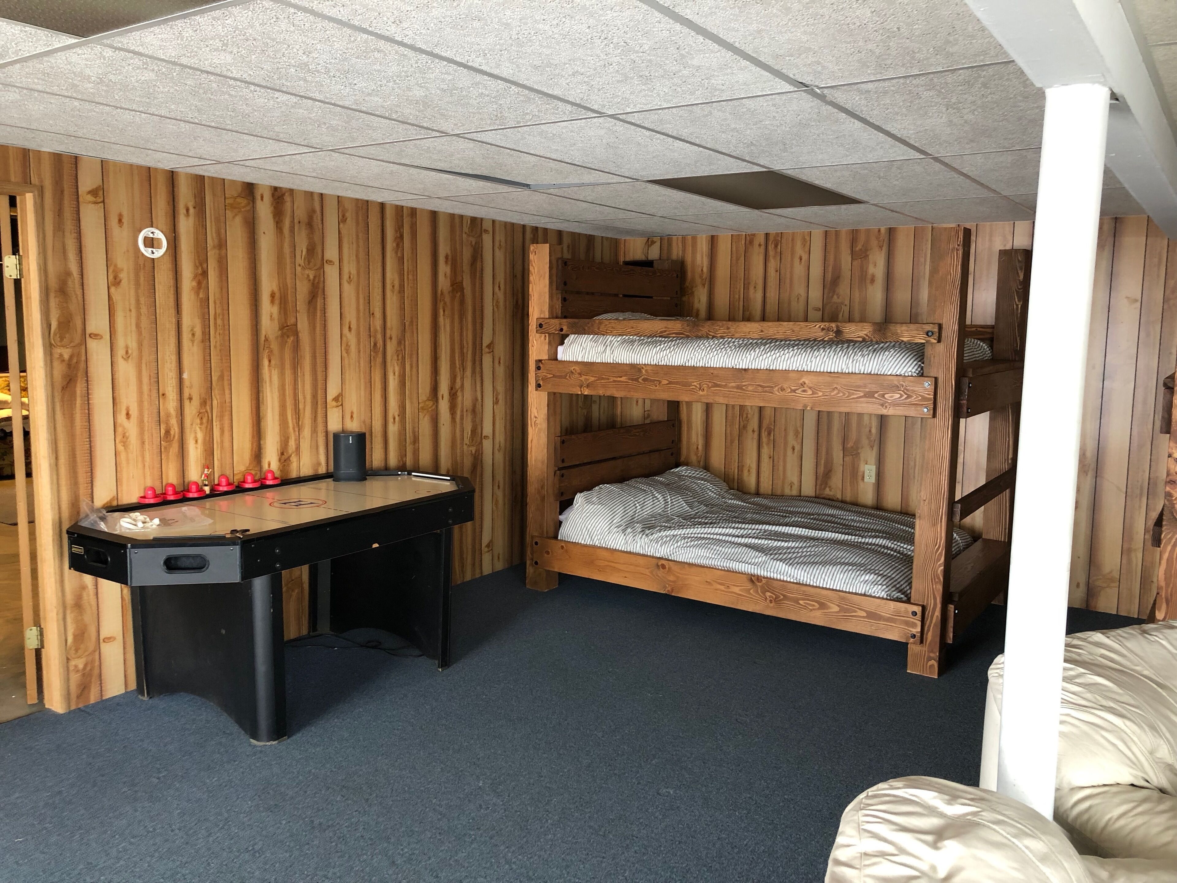 Ein Zimmer mit einem hölzernen Etagenbett, einem Kicker und einem Schreibtisch.