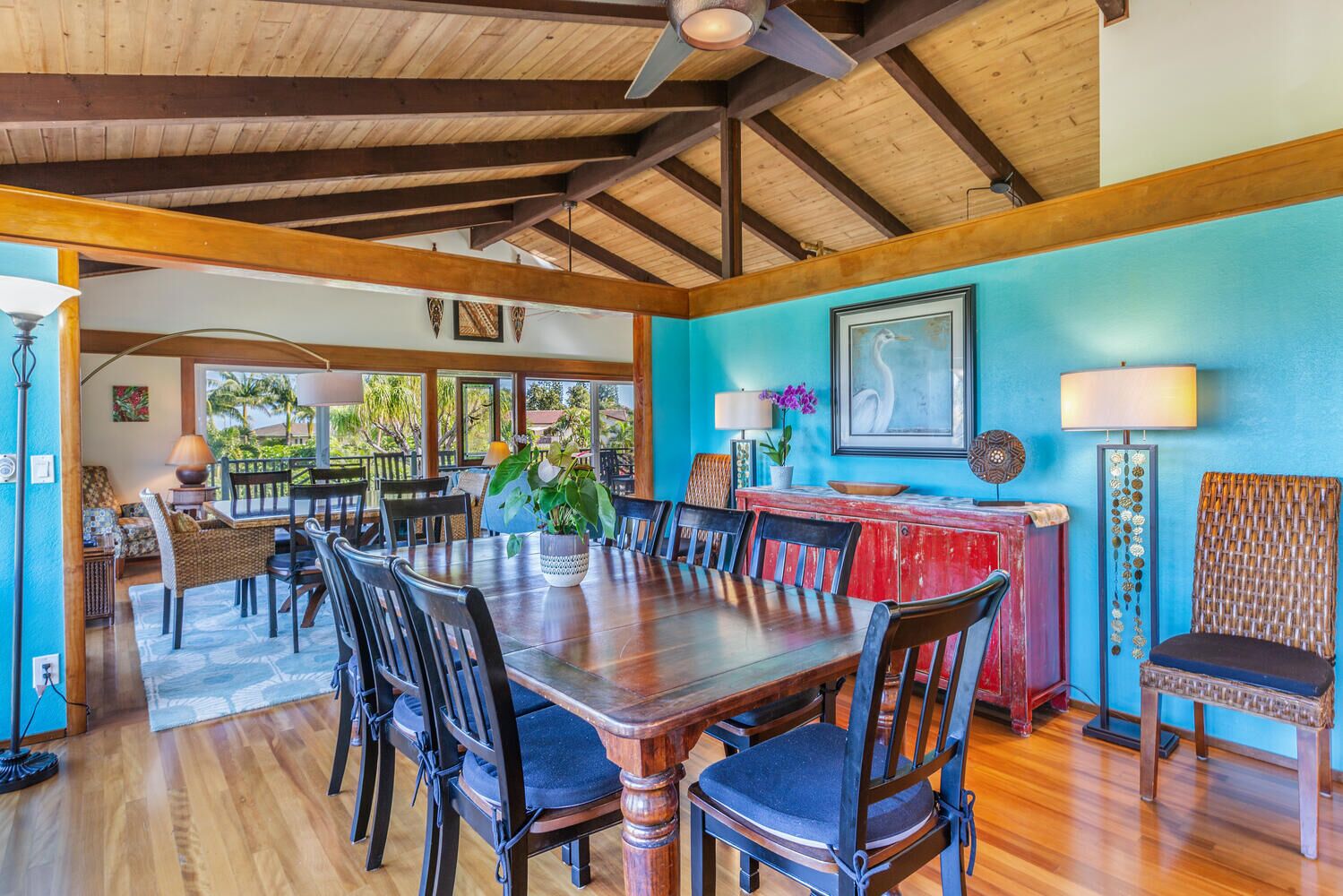 Un comedor con una mesa y sillas de madera, un armario rojo y una pared azul.