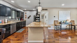 A modern kitchen with dark cabinetry, a granite countertop, and a central island. - Walk to Old Town, 3BR + Backyard (Scottsdale)