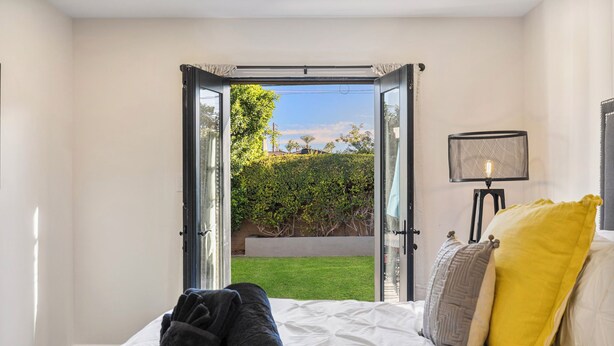 A bedroom with a bed, a window, and a view of a garden. - Walk to Old Town, 3BR + Backyard (Scottsdale)