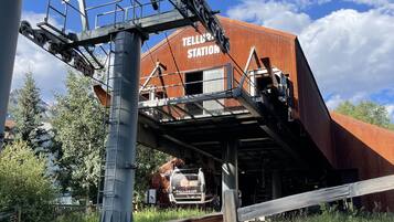 Una estación de tren con un edificio rojo identificado con el letrero "TELLURIPE STATION" y un tren en las vías.