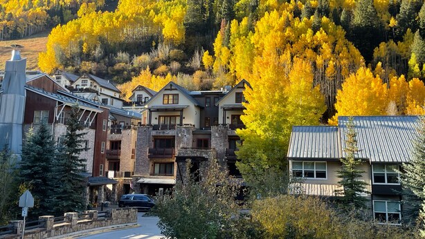 Une ville de montagne qui présente une variété de bâtiments, notamment un chalet à la façade en pierre et un bâtiment moderne doté d’un toit en pente.