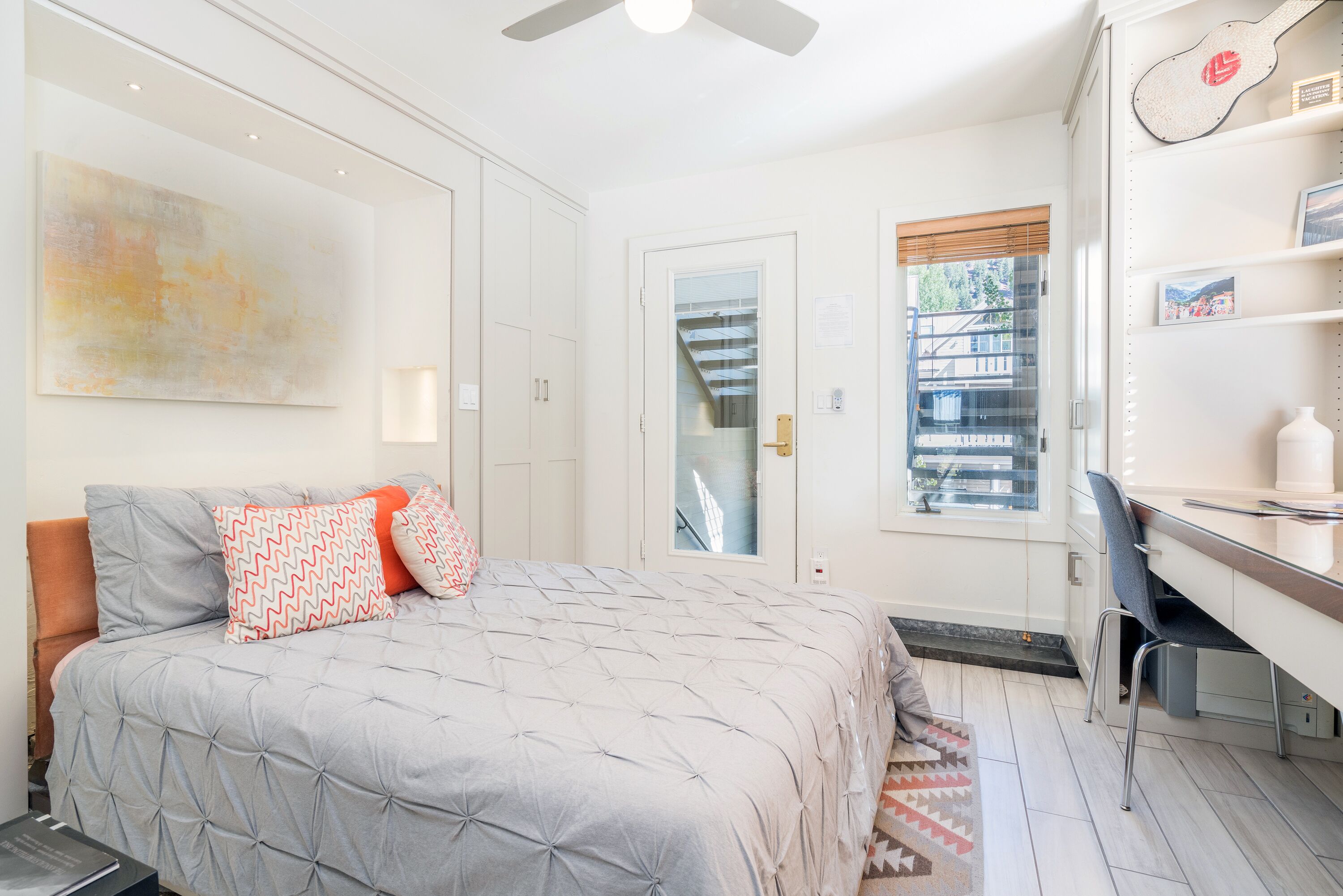 A bedroom with a bed, a desk, and a window.