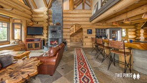 Ein Blockhaus-Interieur mit Kamin aus Stein, Holzmöbeln und einer Bar.