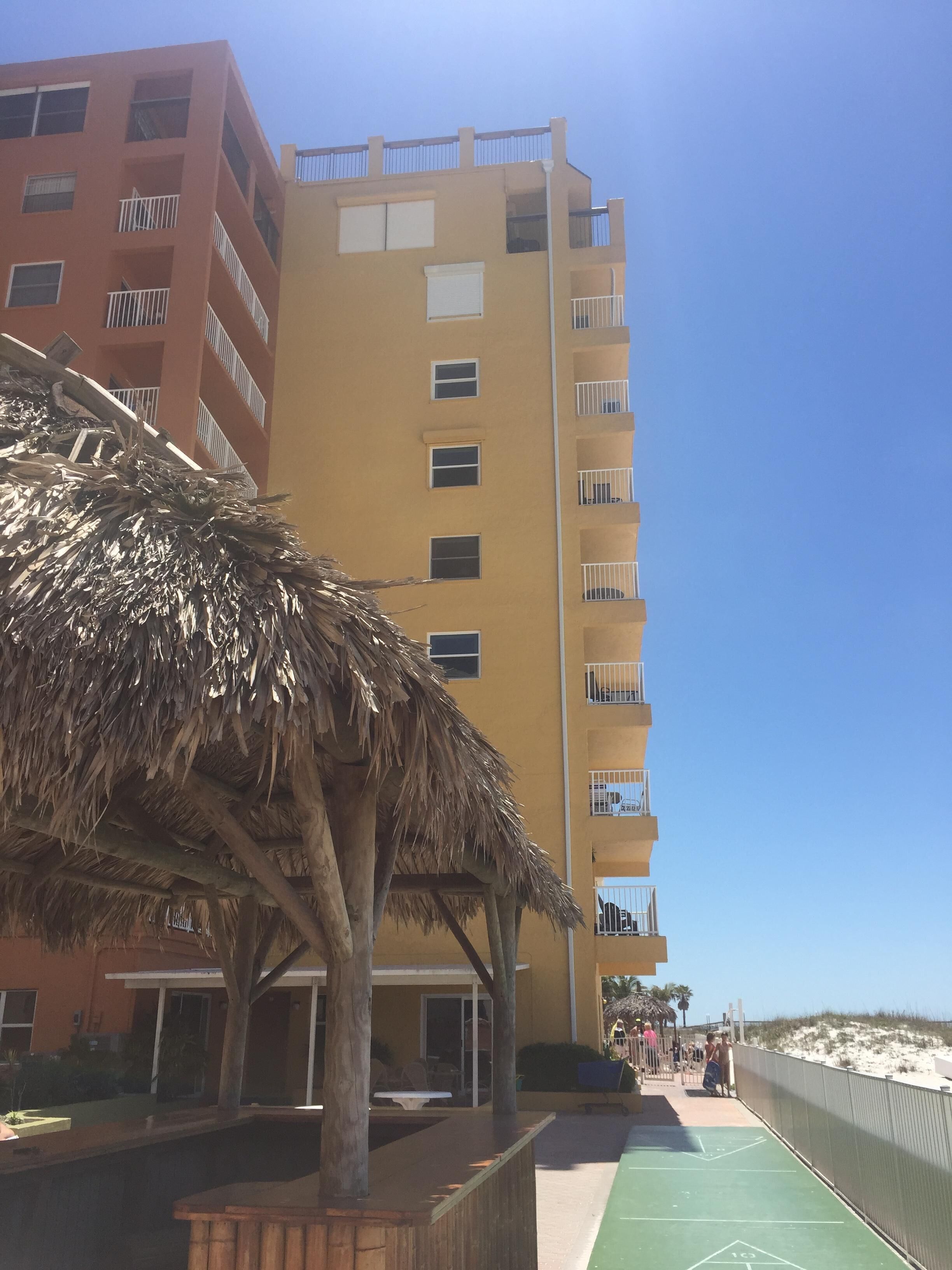 Un hotel de varios pisos con balcones, una zona de piscina y vistas a la playa.