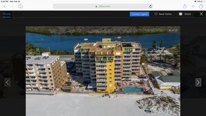 Un hôtel à plusieurs étages doté d’une piscine et d’un accès à la plage, situé près d’une étendue d’eau.
