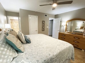 Une chambre à coucher avec un lit, une commode et un ventilateur de plafond.
