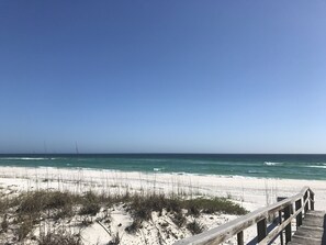 A wooden boardwalk leading to a sandy beach with ocean views.