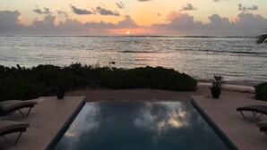 Una piscina con vista al océano y al atardecer.