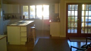A kitchen with a central island, wooden cabinets, and a view through the windows. - Bainbridge Island (Puget Sound):No-Bank Waterfront Sandy Beach (Bainbridge Island)