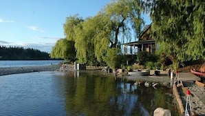 A lakeside property with a wooden dock, a small building, and a weeping willow tree. - Bainbridge Island (Puget Sound):No-Bank Waterfront Sandy Beach (Bainbridge Island)