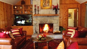 Ein gemütliches Wohnzimmer mit Ledersofas, einem Kamin und einem steinernen Kaminumrandung.