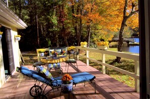A wooden deck with outdoor furniture, a white fence, and a lake view.