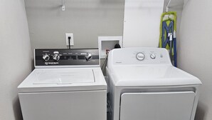 A laundry area with a front-loading washer and a top-loading dryer. - Base Camp / Bonanza (Thompson springs)