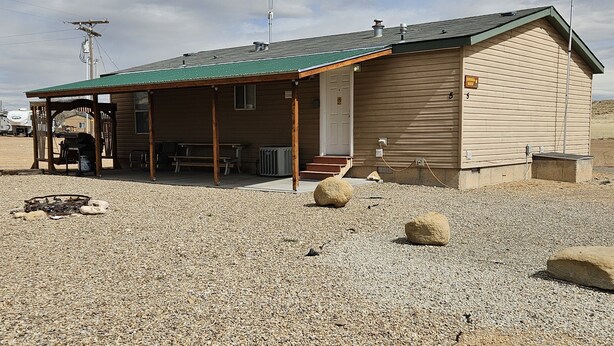 A building with a covered porch, a small entrance, and a gravel ground. - Base Camp / Bonanza (Thompson springs)