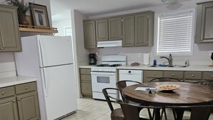 A kitchen with a refrigerator, stove, oven, and sink. There is a dining table with chairs. - Base Camp / Bonanza (Thompson springs)
